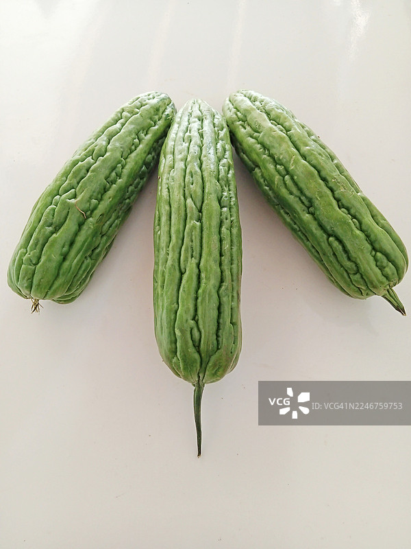 俯视角度拍摄的三个新鲜苦瓜，干净的白色背景图片素材