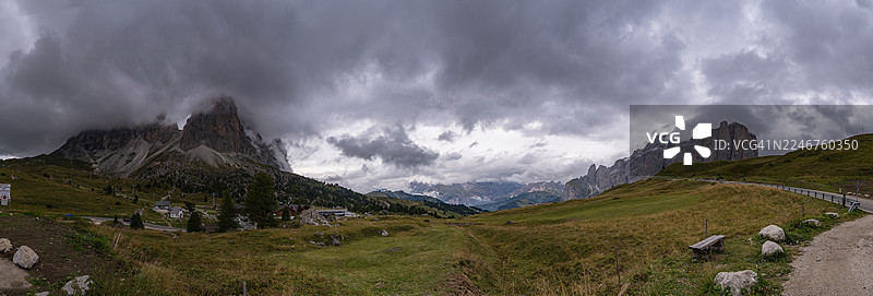 多洛米蒂山脉的壮丽全景，天空多云，有绿色牧场和蜿蜒的道路，位于意大利的瓦尔加尔代纳地区塞勒瓦。图片素材