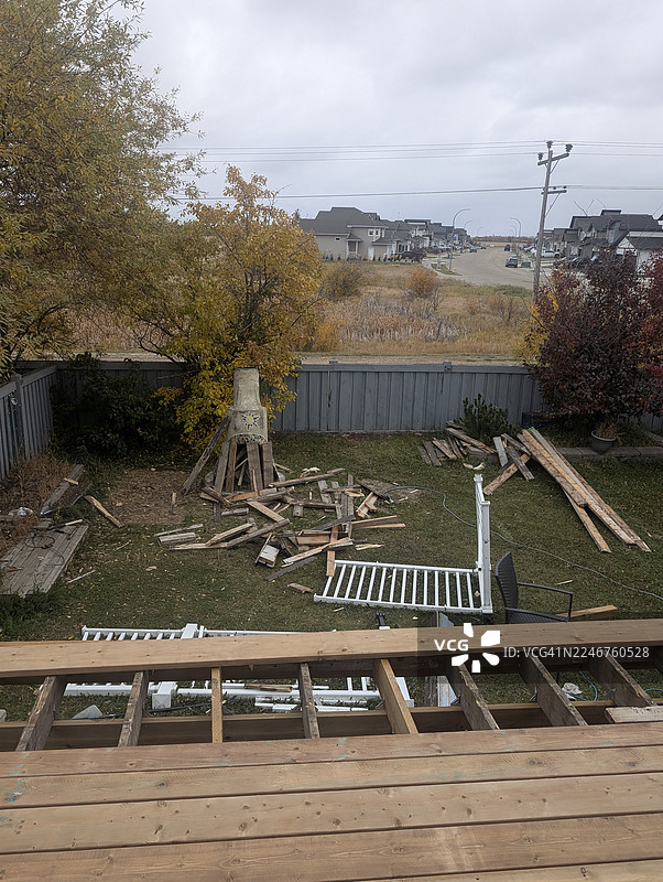 从高处俯瞰杂乱的后院，有建筑垃圾、未完工的露台，背景是加拿大居民住宅，天空多云。图片素材