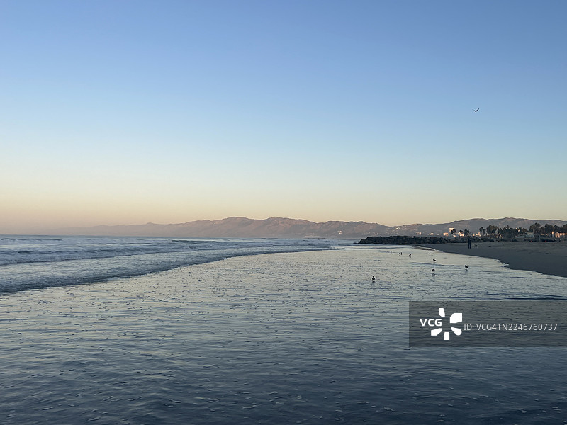 日落时分，远处有山脉的海滩和海洋风景，美国洛杉矶，威尼斯海滩图片素材