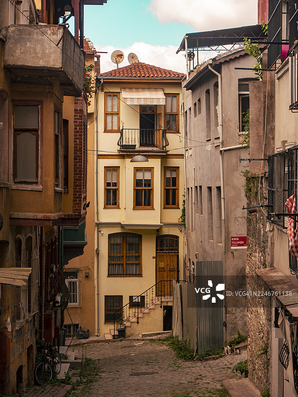 从低角度看，一座古老城镇小巷里的住宅楼在生机勃勃的天空映衬下，土耳其伊斯坦布尔，拜占庭图片素材