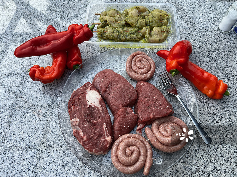 从高处俯瞰石头桌上准备烧烤的各种生肉、香肠和辣椒图片素材