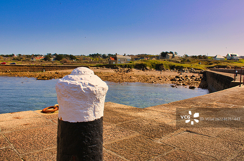 晴天从码头看到的法国费尔芒维尔海岸村庄和岩石海滩的风景图片素材
