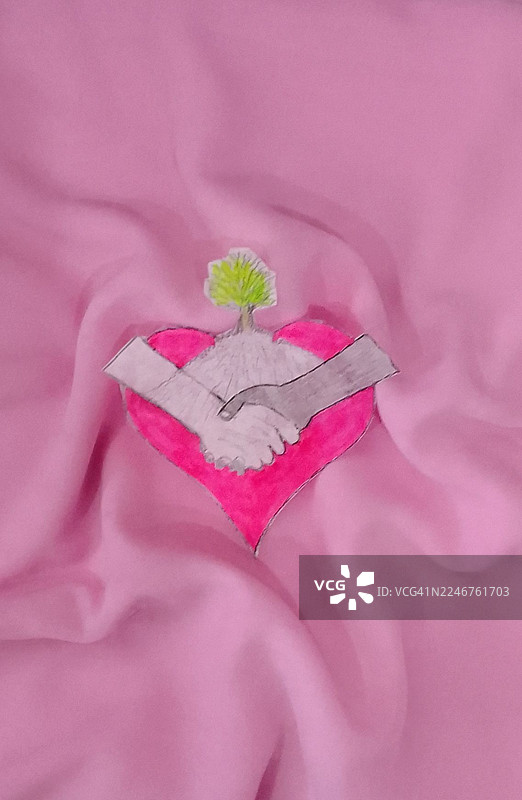 俯视视角，一个粉色的枕头上有爱心、树和握手剪纸，象征着团结与成长图片素材