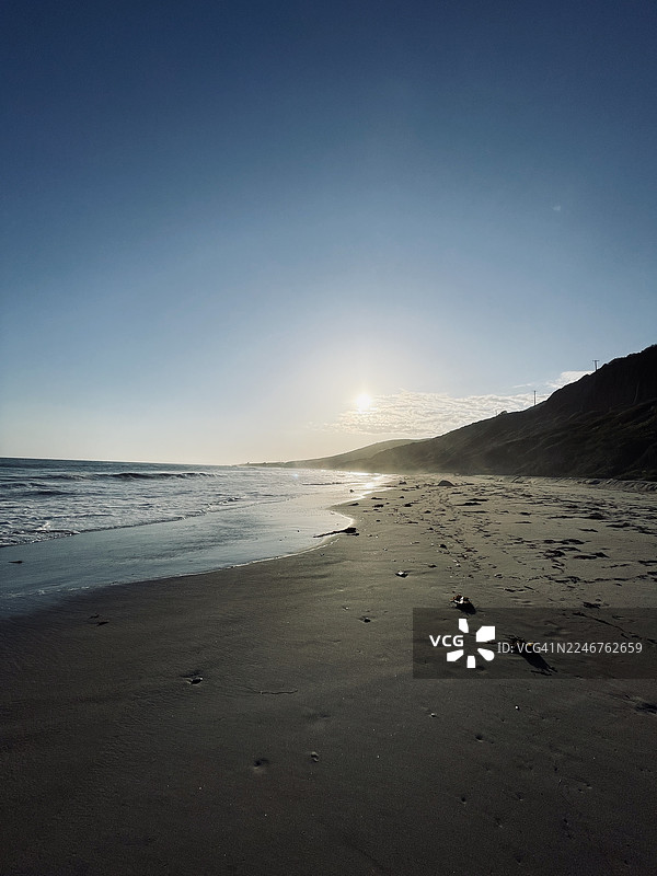 夕阳下的海滩美景，有海浪和晴朗的天空图片素材