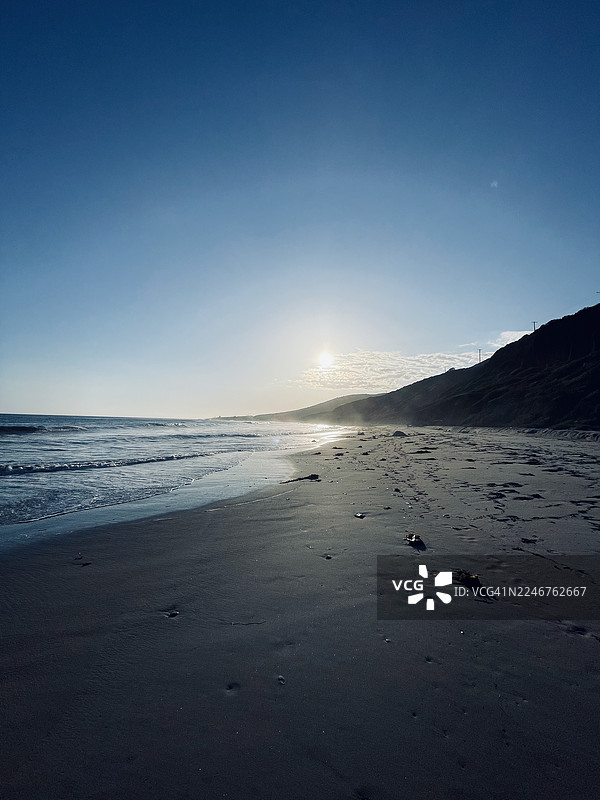日落时分海滩的风景，天空晴朗，海浪平静图片素材