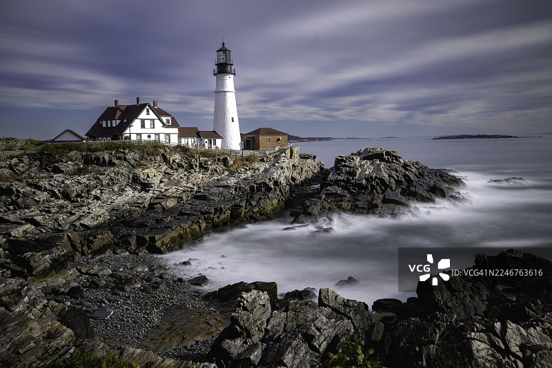 美国，凯普伊丽莎白，威廉斯堡公园，岩石海岸上的历史灯塔和灯塔看守员小屋，戏剧性的天空和长曝光的水景图片素材