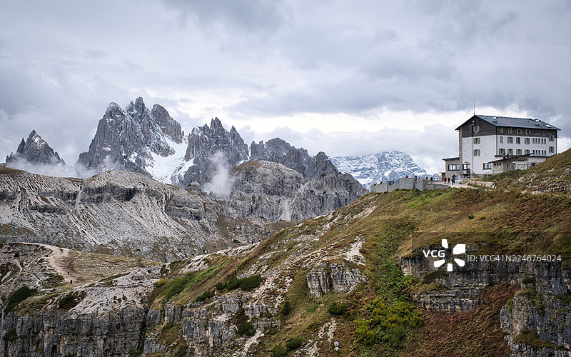 意大利奥朗佐迪卡多雷，山间小屋的全景，周围是崎岖的山峰和阴沉的天空，Rifugio Auronzo图片素材