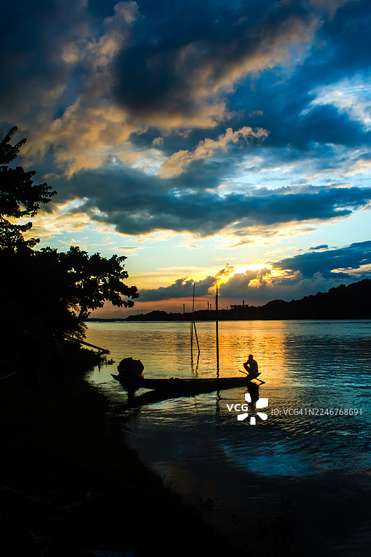 日落时分，孟加拉国吉大港，一人在海中船上的风景，背景是天空图片素材