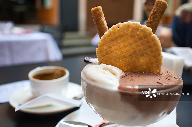 咖啡搭配美味的冰淇淋甜点、华夫饼和威化卷，摆放在户外咖啡馆的桌子上图片素材