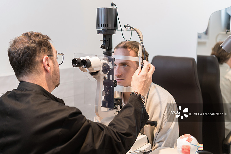 验光师正在使用裂隙灯检查年轻成年患者的眼睛图片素材