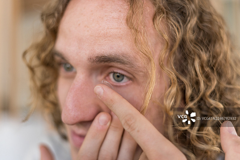 一名年轻男子正在将隐形眼镜放入眼中图片素材