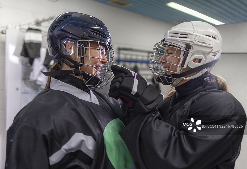 两位戴着头盔的快乐女冰球运动员在更衣室里图片素材