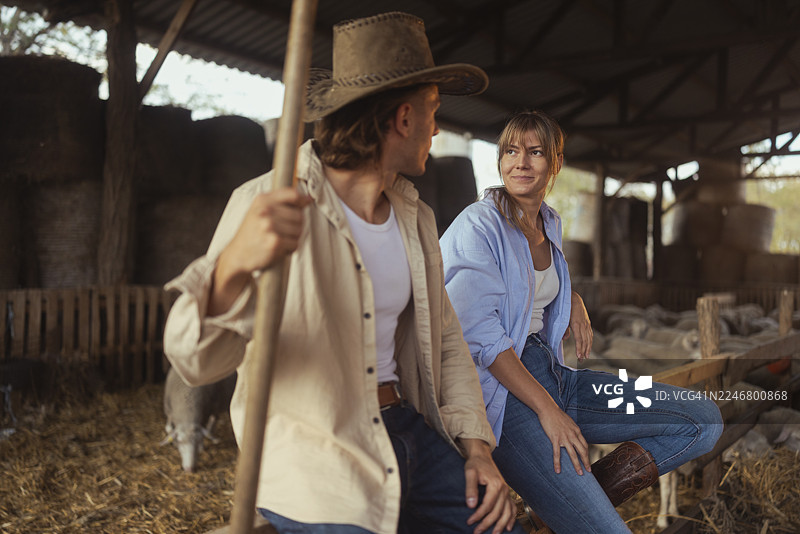 真实的农场生活：两位牧场主在羊群旁休息图片素材