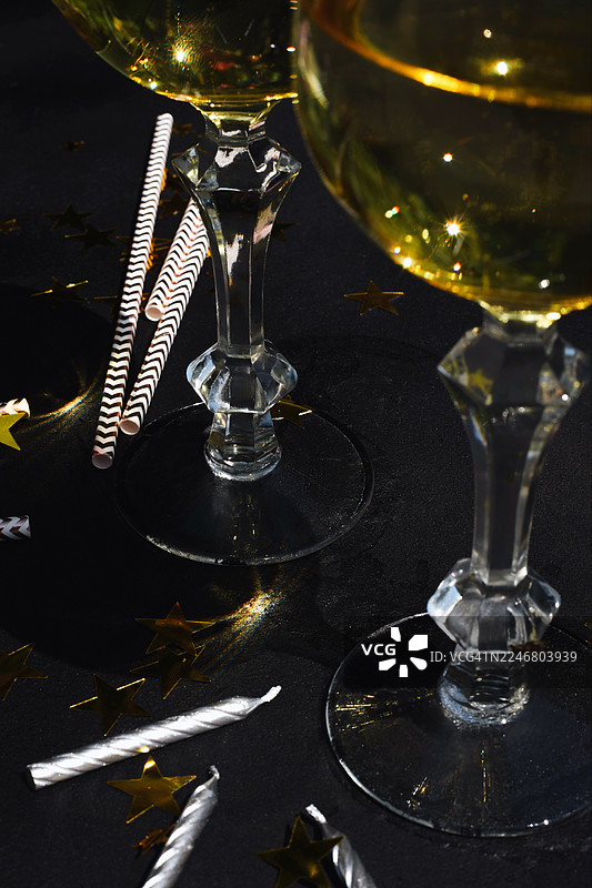 眼镜、香槟、派对帽和纸屑的背景。节日背景。生日。派对的余波。热闹的乐趣。图片素材