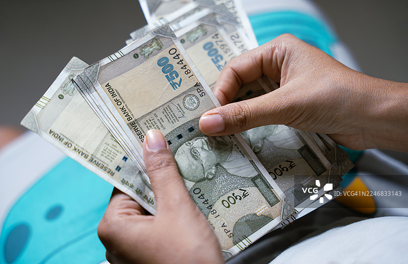 一个人在数一叠印度500卢比的钞票图片素材