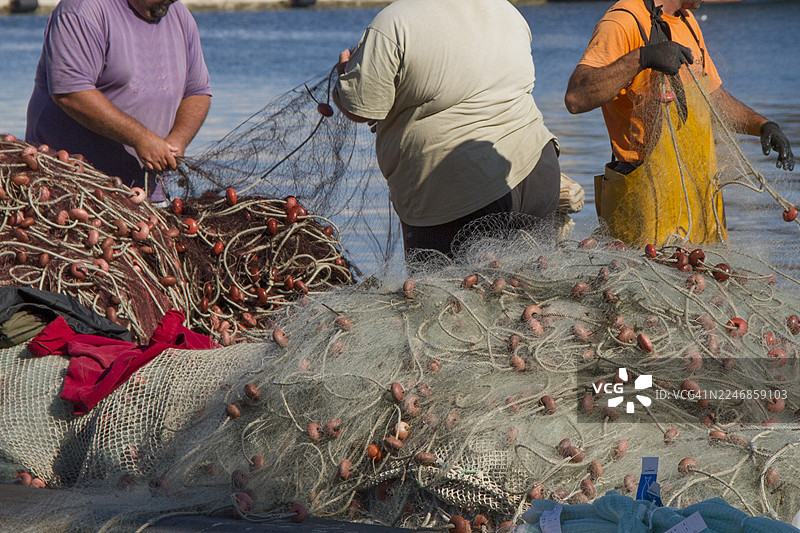 渔民在码头修补渔网图片素材