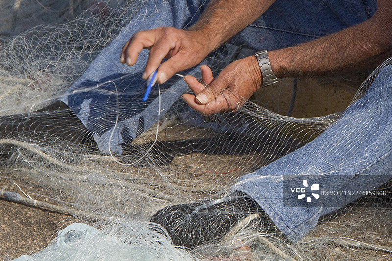 渔民在码头修补渔网的特写图片素材