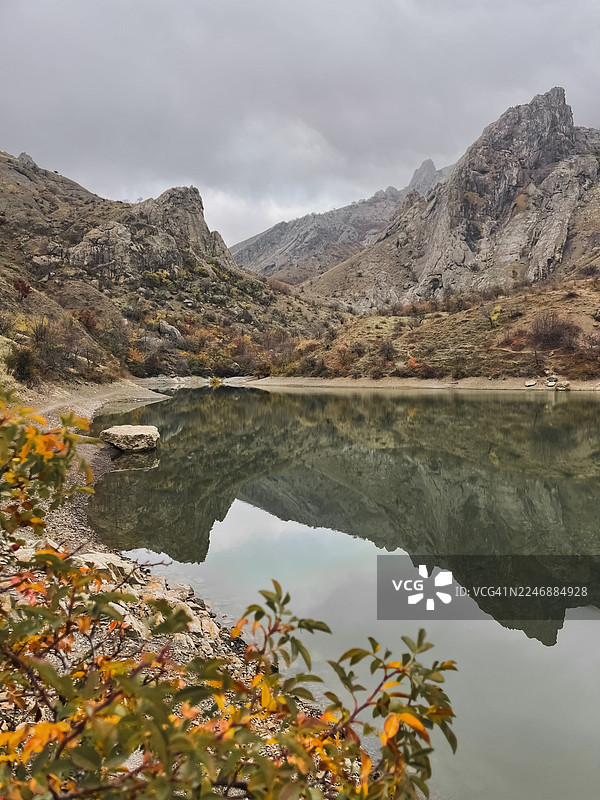 秋日多云天空下，宁静的山湖倒映着崎岖的山峰图片素材