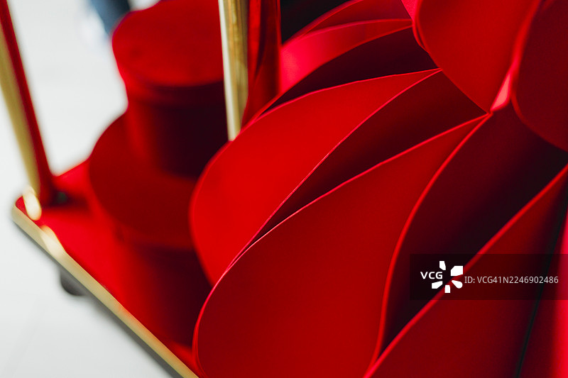 一个鲜红的纸灯笼放在一个镀金的行李车上，行李车上载有深红色的圆柱形礼品盒。图片素材