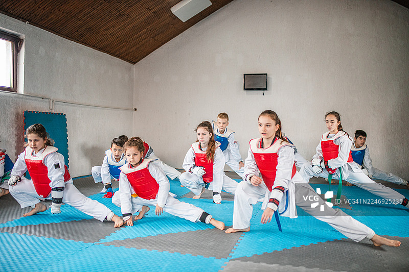 一群年轻的跆拳道学员在训练开始前进行拉伸图片素材