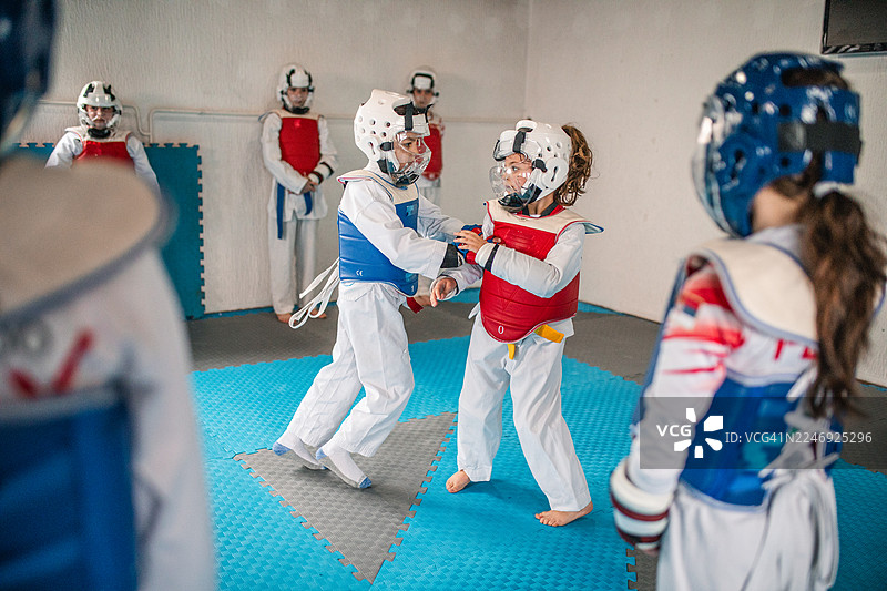 一群年轻的跆拳道选手正在练习动感的腿部踢击和成对的实战演练图片素材