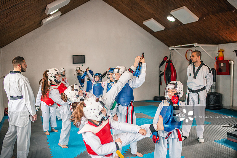 一群穿着白色跆拳道服和护具的男孩女孩正在激烈地对练图片素材