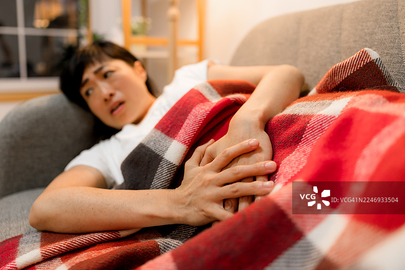 一位女士痛苦地捂着肚子，面部扭曲图片素材