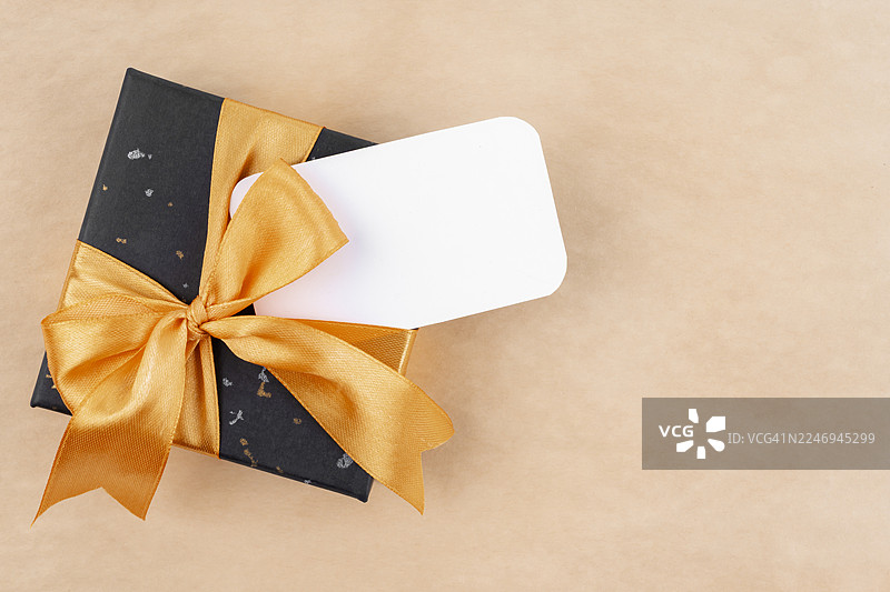 棕色背景上的黑色礼品盒，带有空白标签供您添加文字。图片素材