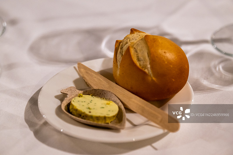 白色盘子上的面包卷和香草黄油图片素材