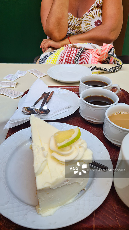 一位女士在咖啡馆享用柠檬蛋糕和咖啡图片素材