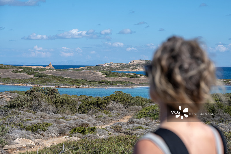 希腊安提帕罗斯岛，女子背对镜头眺望大海，背景是晴朗的蓝天图片素材