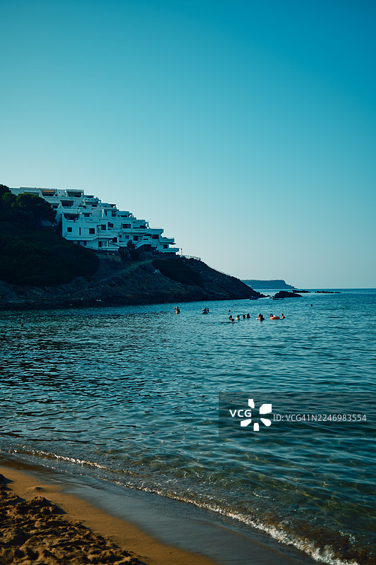 海滩游客在地中海清澈的蓝色海水中游泳图片素材