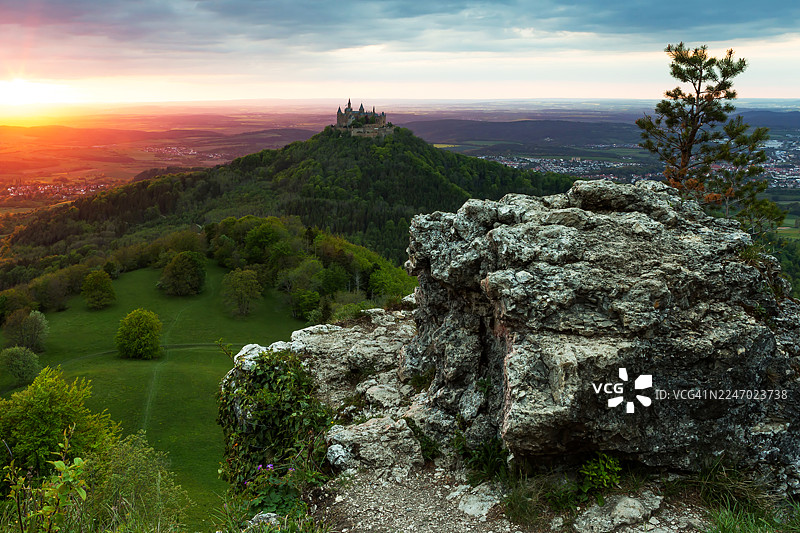 德国巴登-符腾堡州旅游目的地地标霍亨索伦城堡，日落时分，前景有一块大石头图片素材