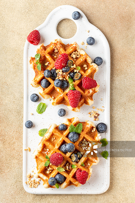 俯视拍摄的两块华夫饼，配有新鲜浆果和薄荷叶图片素材