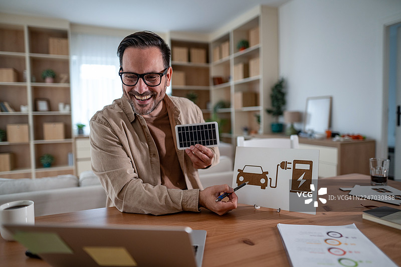 男人展示太阳能电池板和电动汽车充电概念图片素材