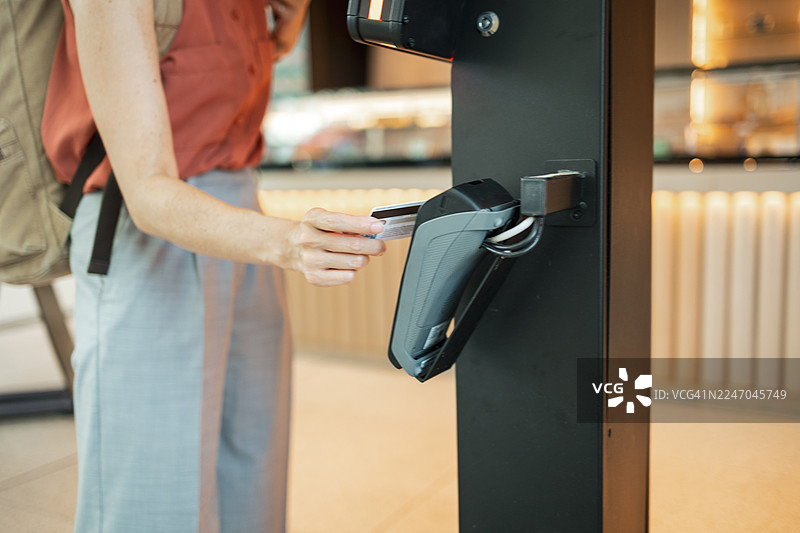 女子在咖啡馆的自助结账机上使用非接触式信用卡付款图片素材