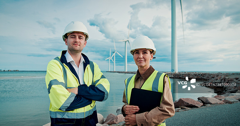 风力涡轮机，海岸上的肖像或人们双臂交叉，在系统工程中的自信或职业。风车，岸边的团队或技术人员带着文件，关于我们或丹麦的机械维护。图片素材