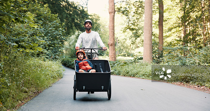 货运自行车，父子二人户外出行，享受环保骑行，探索森林小路或增进亲子关系。安全，父子在自然中骑行，体验可持续交通或探险。图片素材