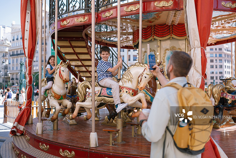 父亲捕捉欢乐的旋转木马骑行瞬间图片素材