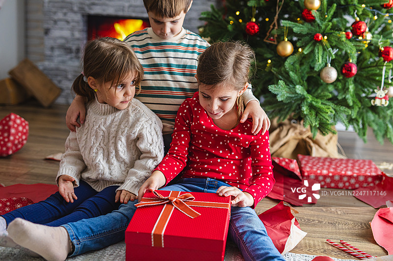 孩子们在圣诞节早晨惊喜地拆礼物图片素材