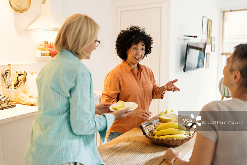 三位女性在温馨的厨房里准备早午餐并聊天图片素材