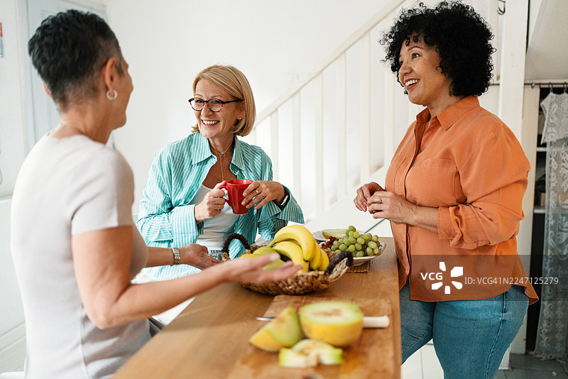 成熟的朋友们在家享用早午餐，品尝水果图片素材