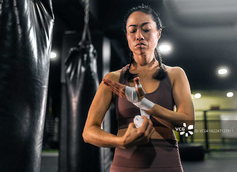 亚洲女运动员在拳击训练前缠手图片素材
