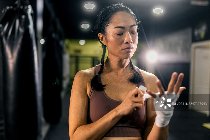 亚洲女运动员在拳击训练前缠绕双手图片素材