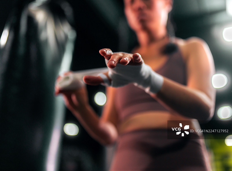 亚洲女运动员在拳击训练前缠绕双手图片素材