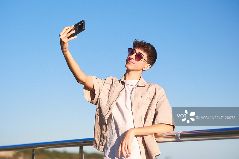 年轻男子在海滨步道上自拍，背景是大海图片素材