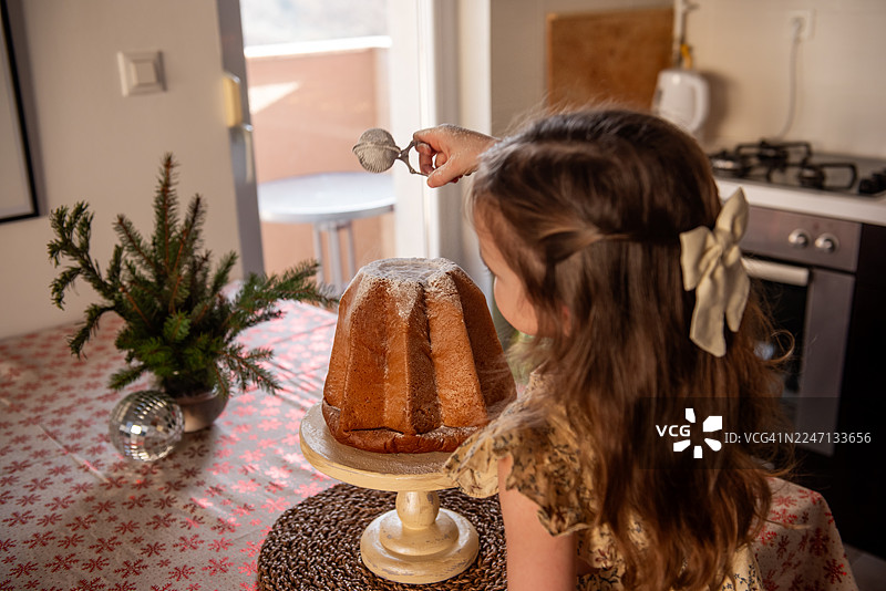 小女孩在圣诞节用糖粉装饰潘多洛面包图片素材