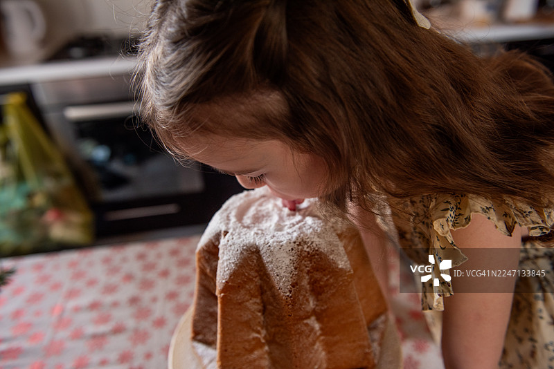 小女孩在享用撒满糖粉的甜美潘多洛蛋糕图片素材
