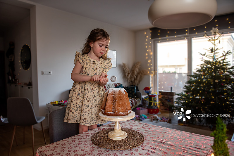 小女孩在圣诞节装饰潘多罗蛋糕图片素材